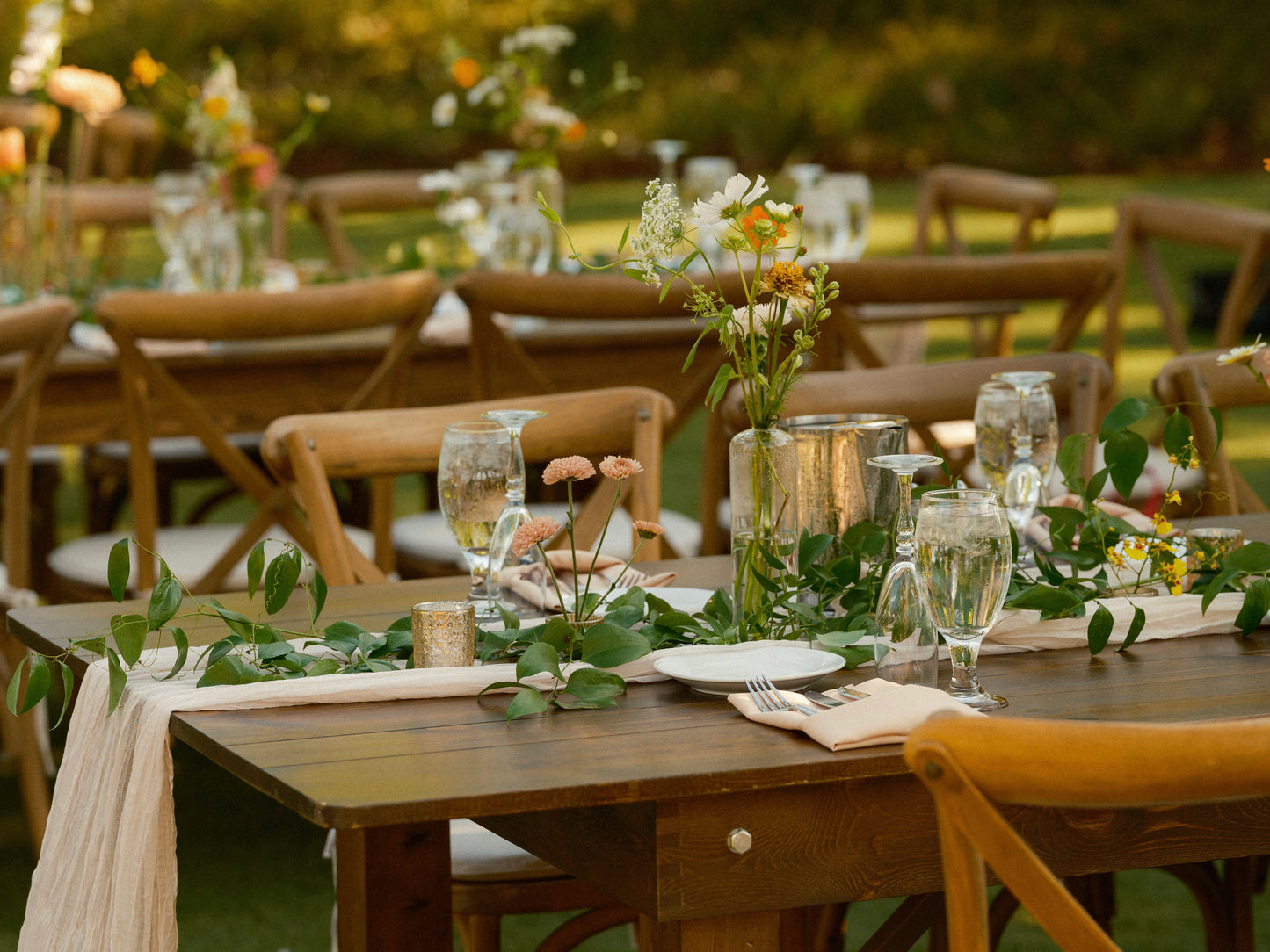 Smilax hand laid greenery garland on a long farm table with bud vases