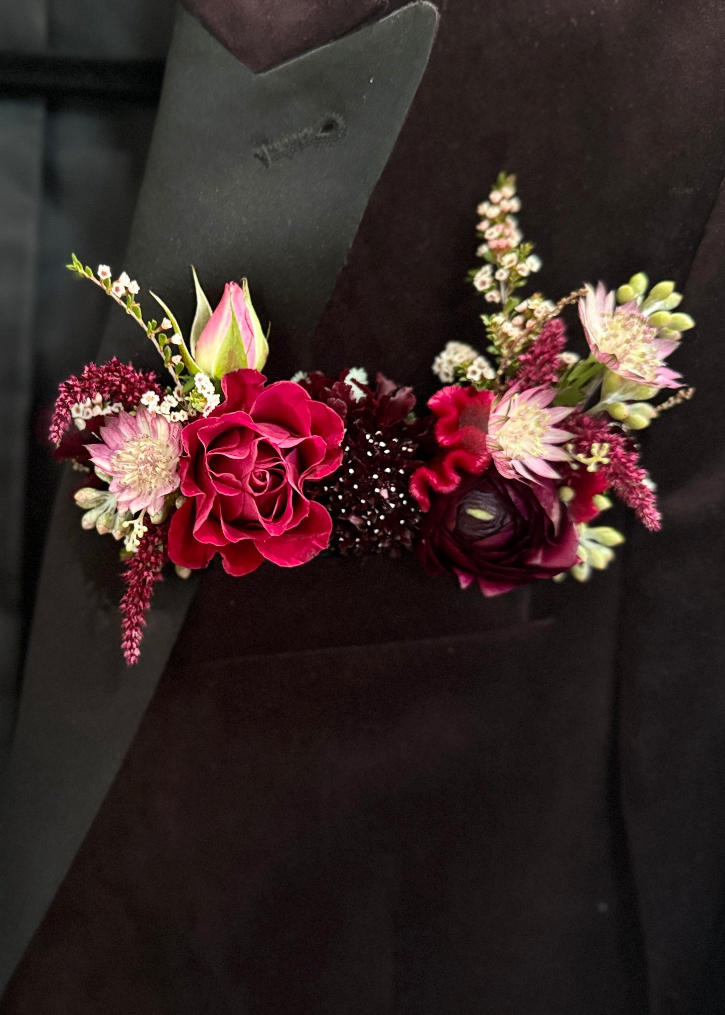 Burgundy pocket square boutonniere in a pocket of a dark suit jacket