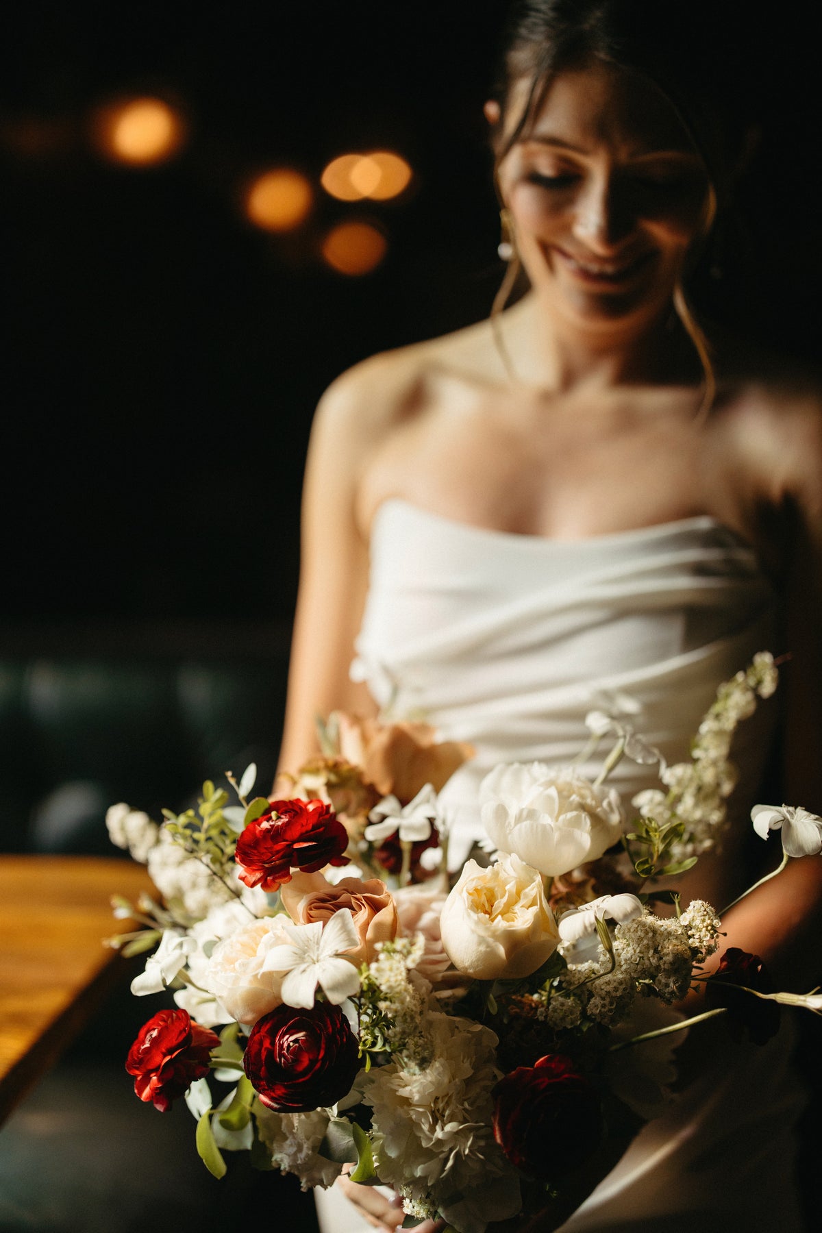 A bride in a strapless white gown holds a premium variety bridal bouquet with white, burgundy and cream flowers for her wedding in Los Angeles.