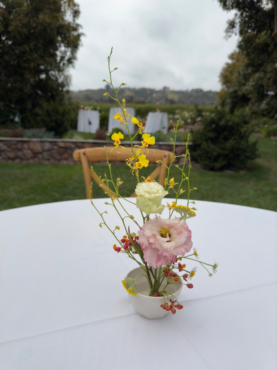 Ikebana style floral arrangement on a cocktail table at an outdoor wedding venue in Los Angeles.