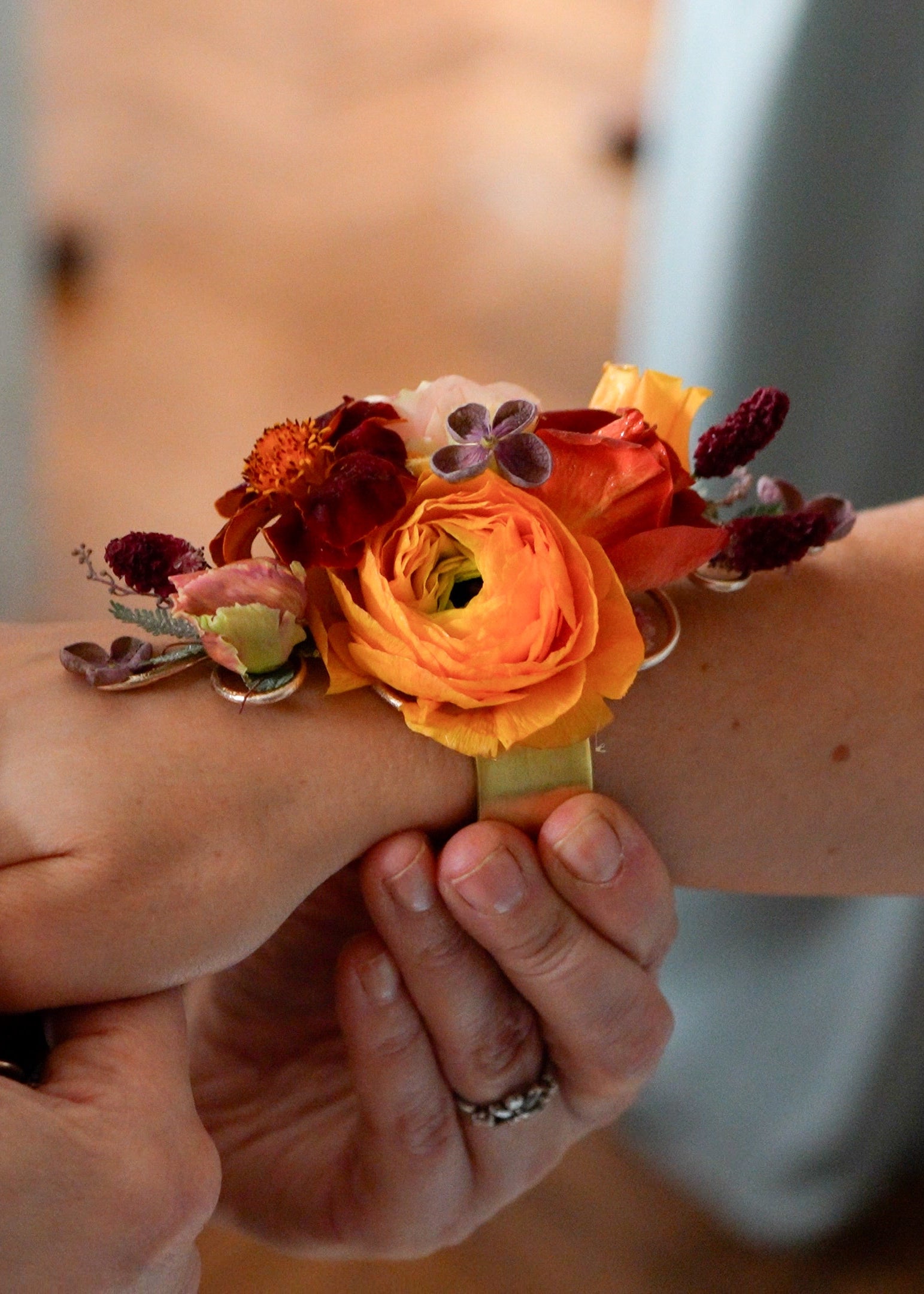A florist placing a fall colored floral wrist corsage.