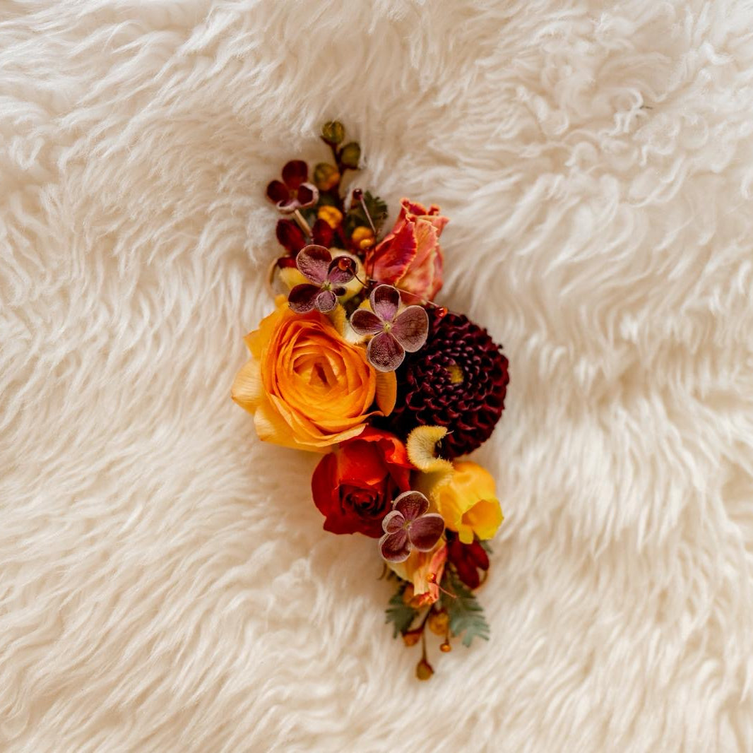 Fall colored jacket lapel piece with burgundy dahlia and peach ranunculus