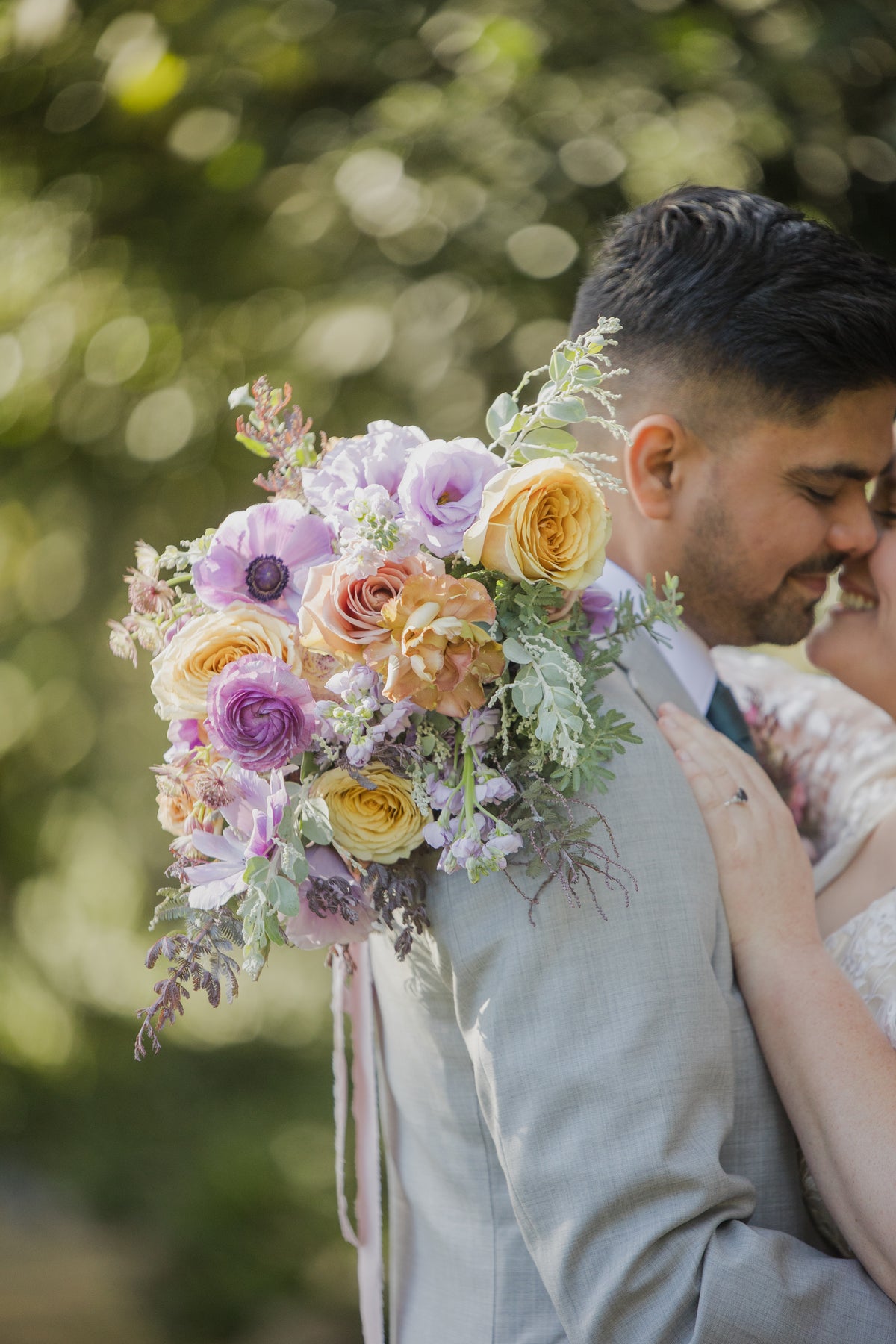 A close-up wedding bouquet featuring shades of purple and gold roses with sage green foliage at a wedding at The Lodge at Malibou Lake in Agoura Hills, CA 91301.