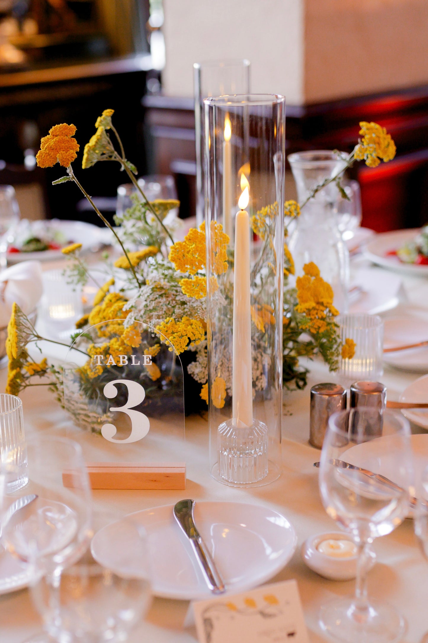 A yellow and white wedding centerpiece with realistic looking LED taper candles at the Ebell of Los Angeles.
