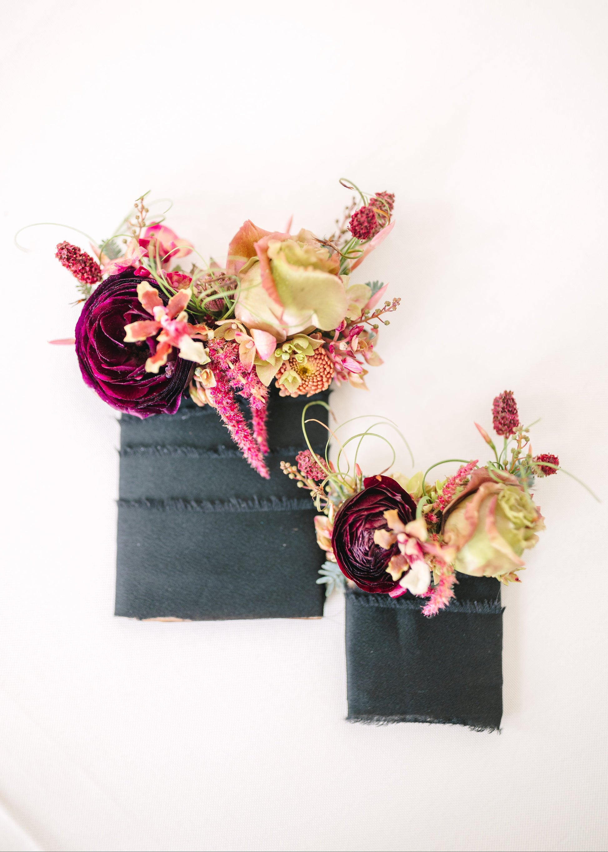 Two dark fabric pocket square boutonnieres for a groom and his son.