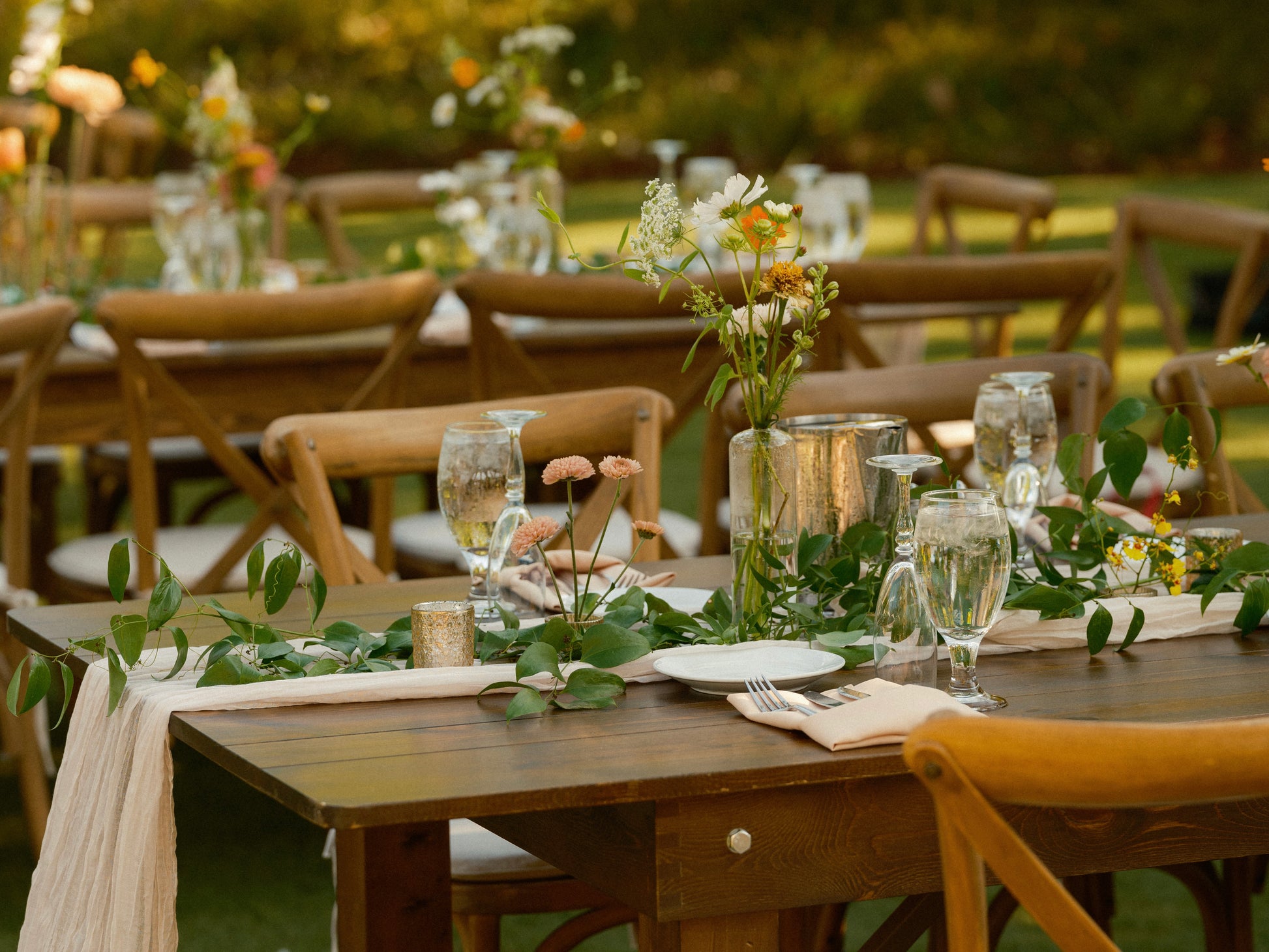 Smilax hand laid greenery garland on a long farm table with bud vases