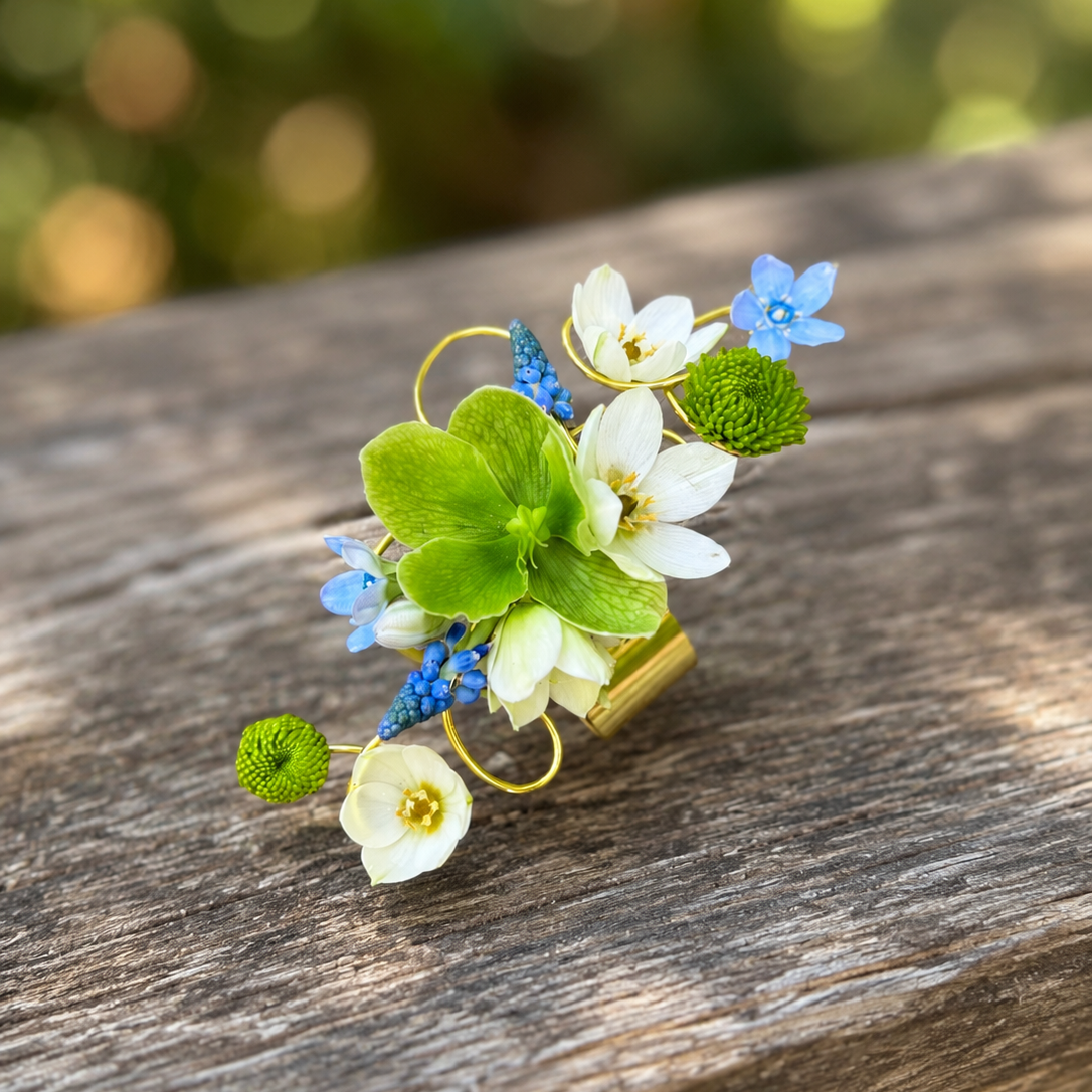 Prom Corsage with green, white, and blue flowers on a gold bracelet cuff